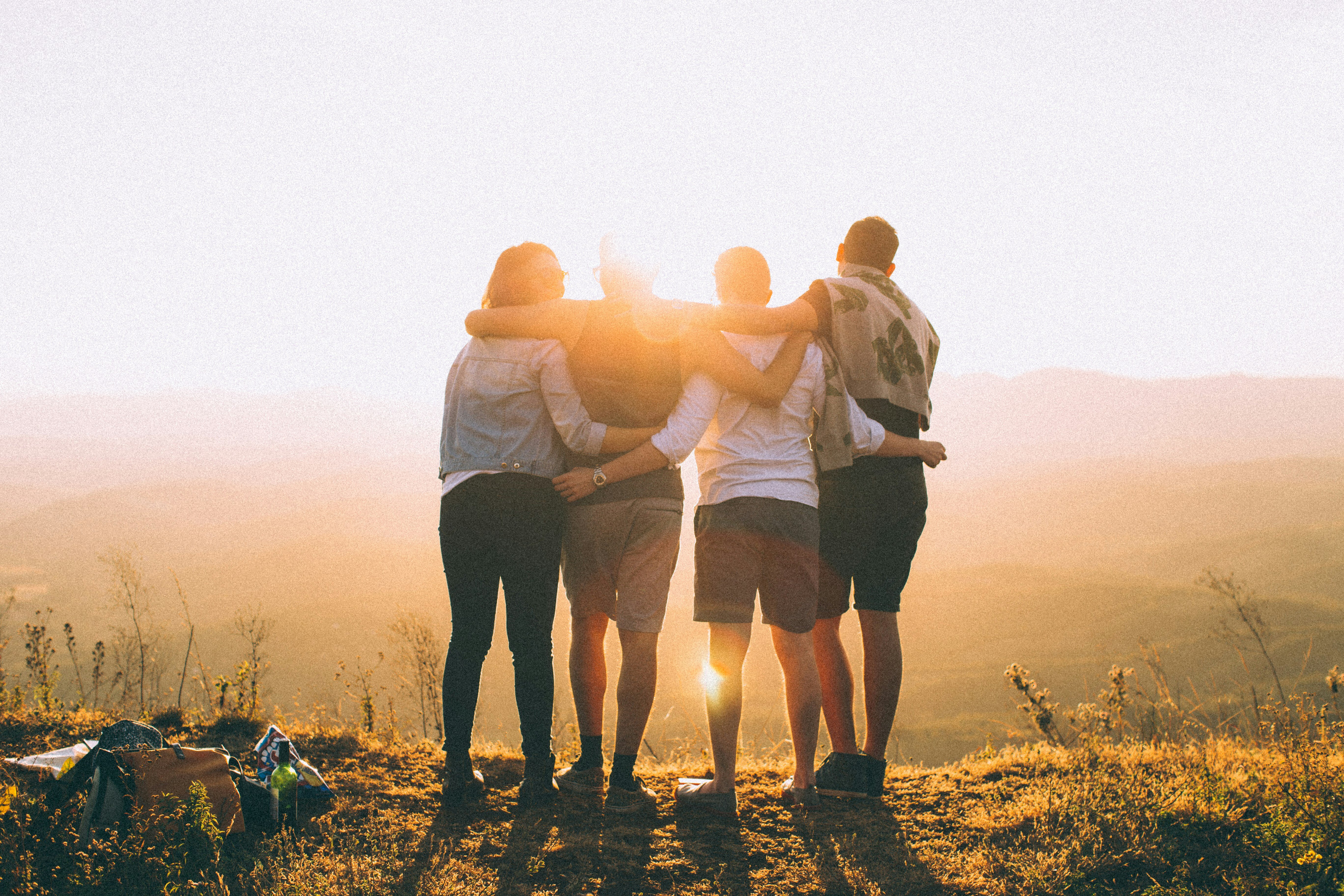 People in Line with Arms Around Each Other Looking Over a Cliff Edge